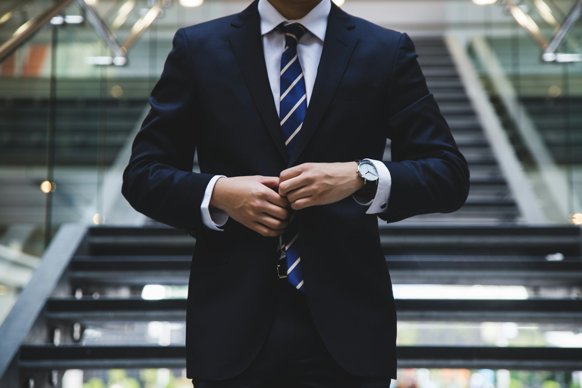 A man wearing a suit adjusting his tie 